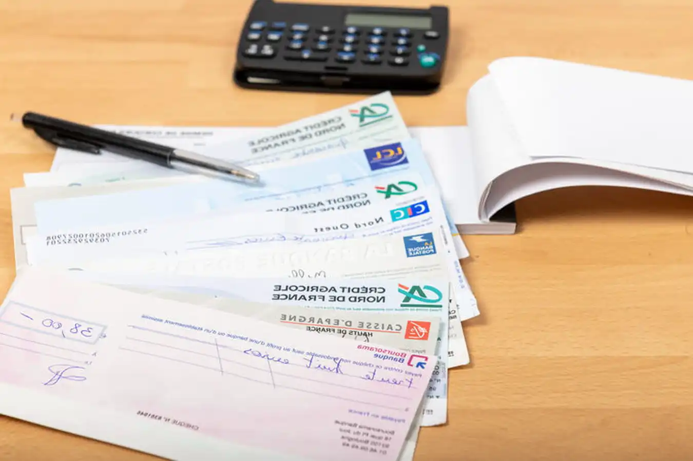 Chèques bancaires servant de garantie locative, avec un stylo et un carnet de chèques sur une table